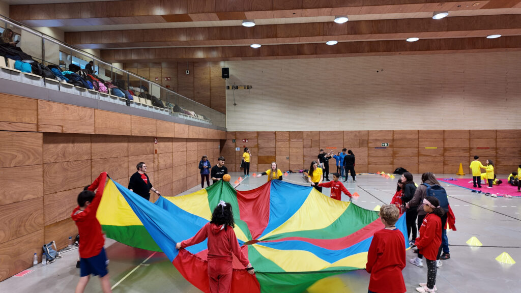 El paracaigudes estès i infants de color vermell agafant-lo al voltant