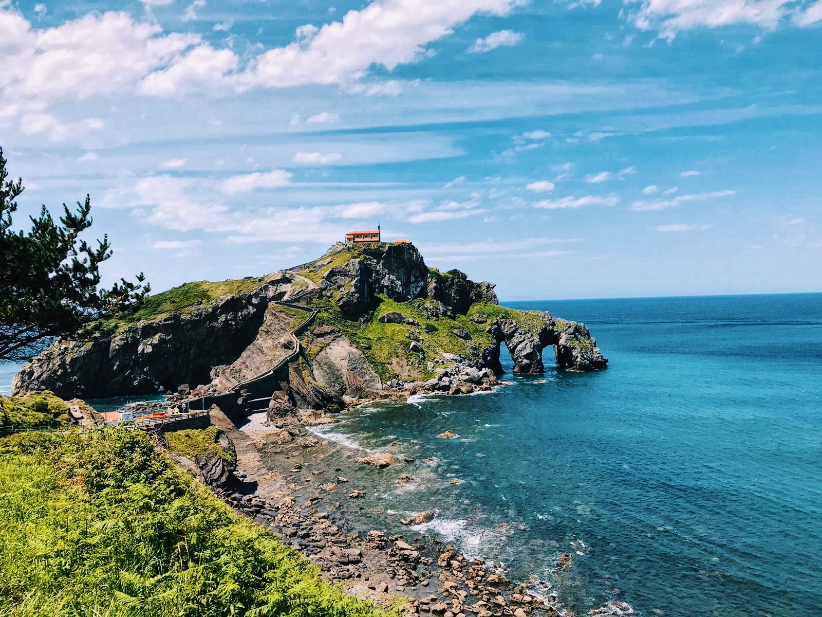 Imatge d'un paisatge d'un barranc i una casa a la punta, veient el mar de fons