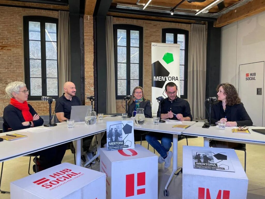 Cinc ponents del webinar Mentora asseguts en una taula en forma d'U en un estudi de gravació, debatent sobre l'abandonament escolar a la Formació Professional al Hub Social de Barcelona