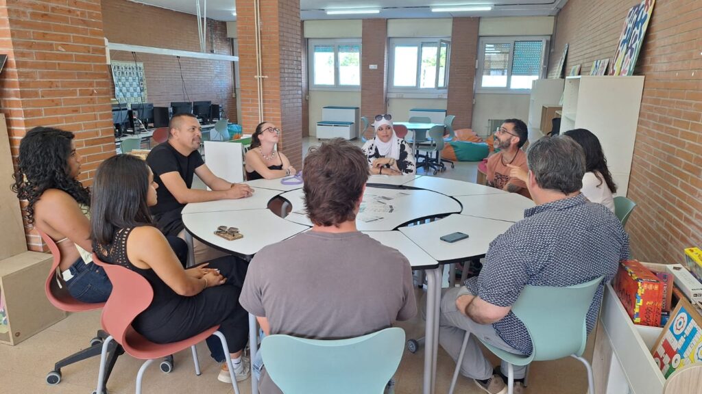 Primera trobada de la xarxa AlumniFP La Bastida, amb una imatge de grup on apareixen exalumnes de l'institut, el director i la coordinadora pedagògica compartint la jornada. Seuen al voltant d'una taula rodona a la biblioteca del centre.