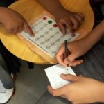 Les mans d'uns alumnes que desxifren un text codificat.