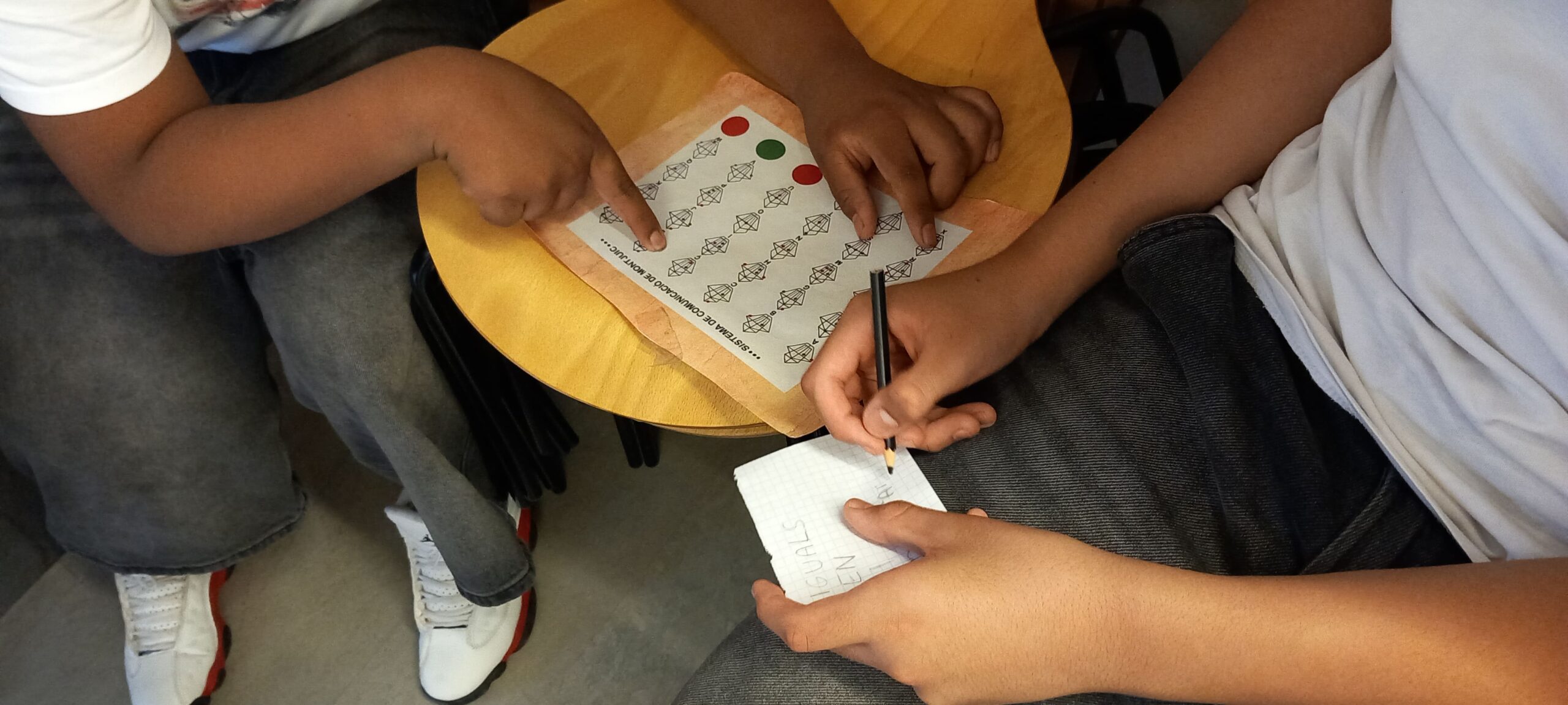 Les mans d'uns alumnes que desxifren un text codificat.