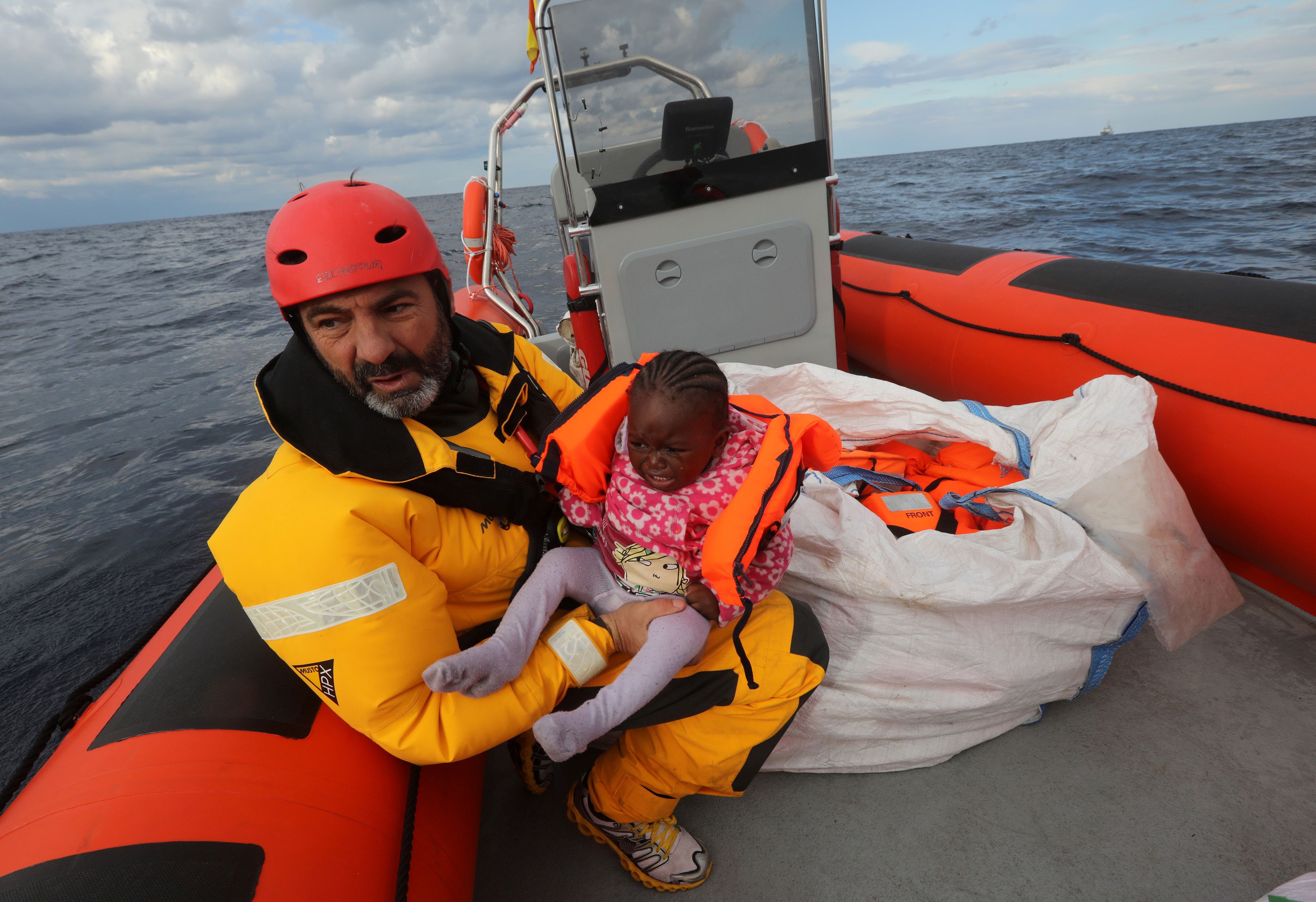 Oscar Camps, founder of Spanish NGO Proactiva Open Arms, holds a migrant child inside a rescue craft after pulling it from an overcrowded raft