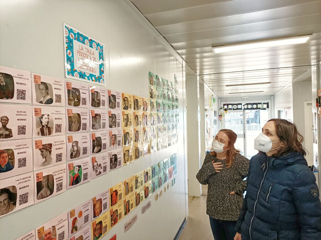 Dues professores observen el mural de dones científiques