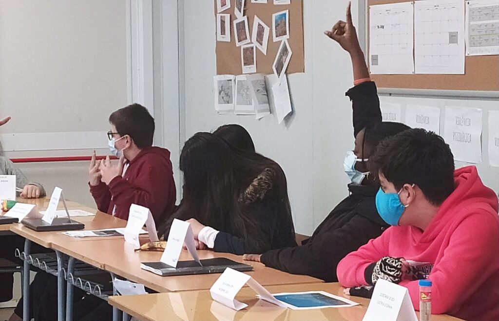 Una alumne aixeca la mà per participar en un debat