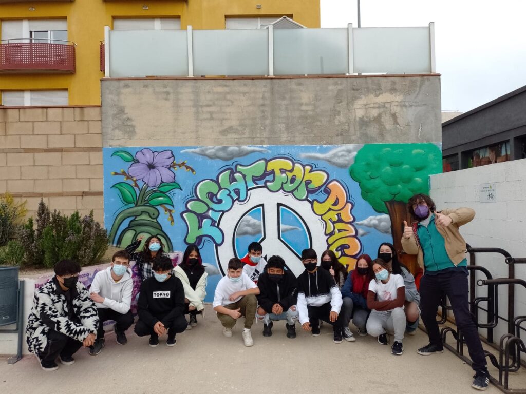 Un grup d'alumnes davant del grafit per la pau del pati