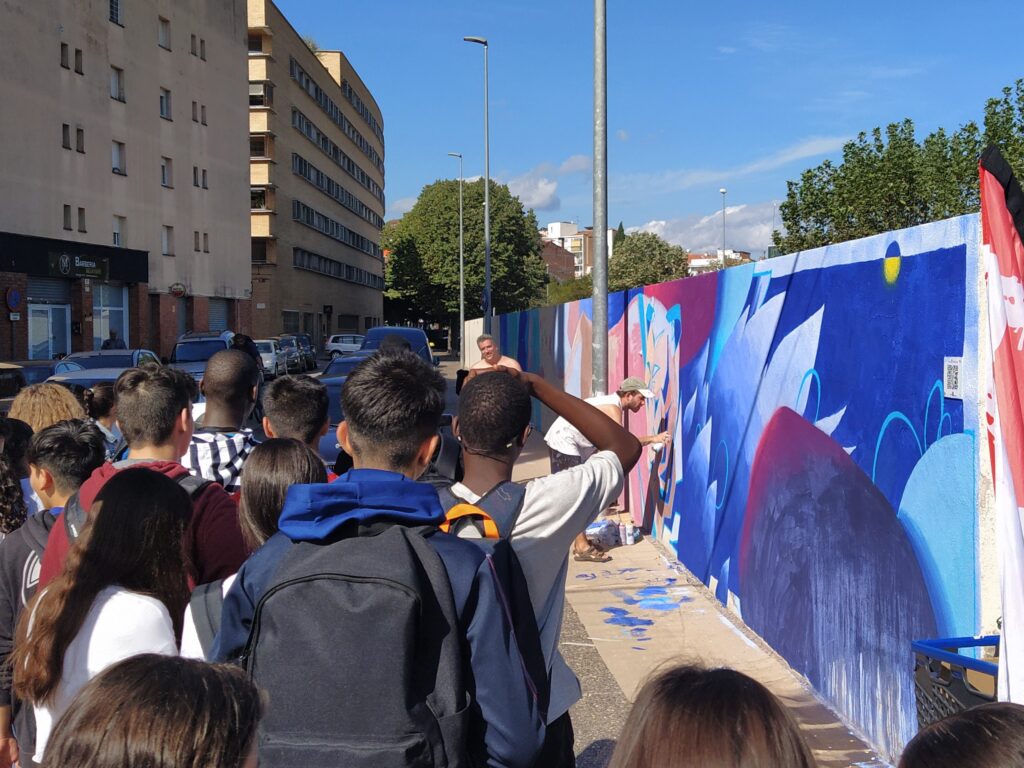 Aprofitant la celebració del festival Monar’t als barris de Santa Eugènia de Ter i de Can Gibert del Pla, el passat dimarts dia 19 l’alumnat de 4t d’ESO de l’optativa d’Expressió Artística va gaudir d’una visita guiada per les diferents obres del festival. A Can Ninetes vam trobar a la nostra guia, que ens va acompanyar a conèixer diferents artistes i veure com treballaven en directe. Monar’T és un festival anual de Murals i d’Art Urbà amb un caràcter 100% social i de temàtica multicultural. Aquest any s’ha celebrat la 5a edició del festival, coincidint amb el 25è aniversari del Centre Cívic Santa Eugènia i el que es considera 50è aniversari del naixement de l’art urbà.