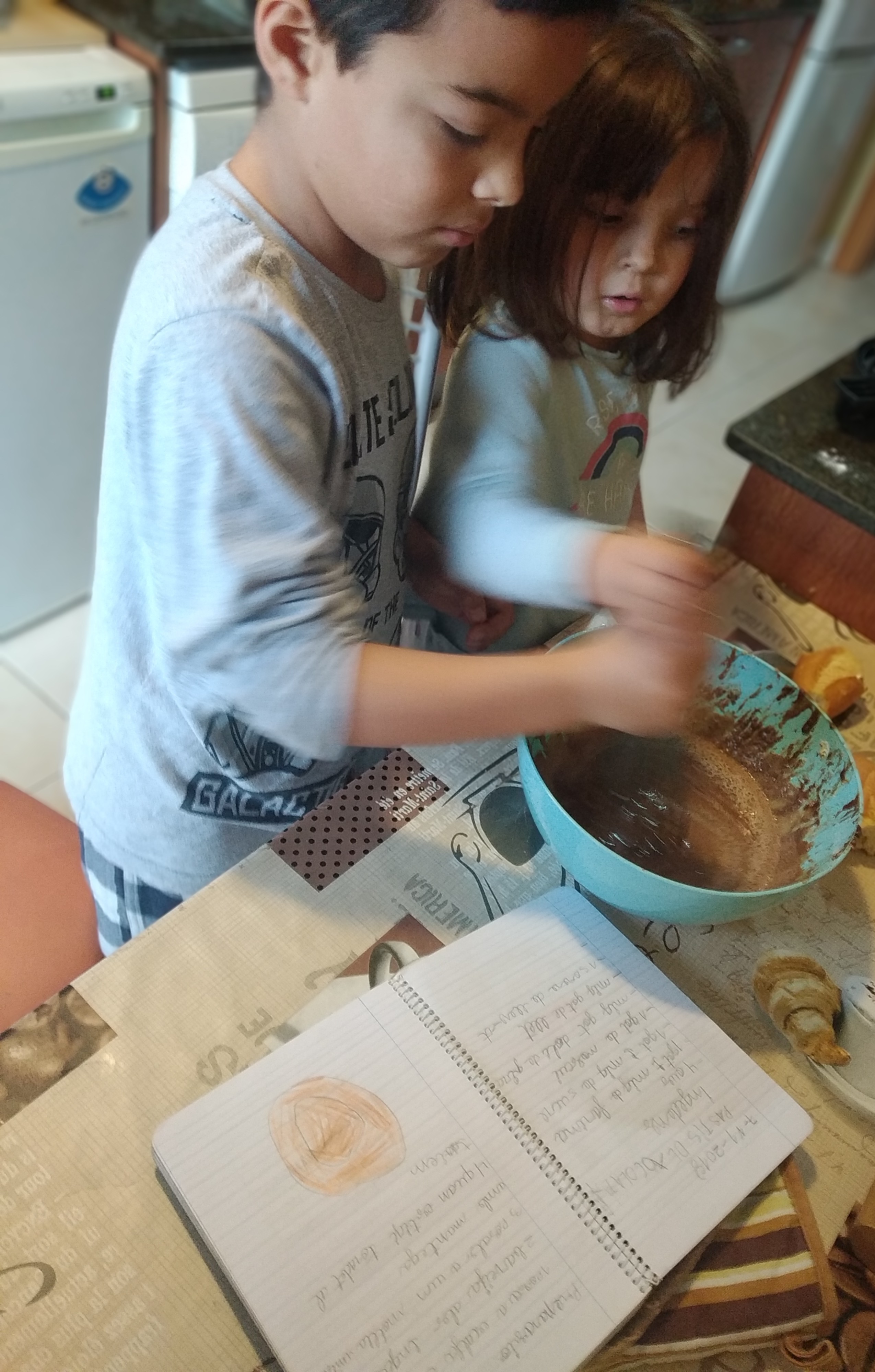 L'Èric de 3r i la Júlia de P3 seguint la recepta per a fer un pastís de xocolata