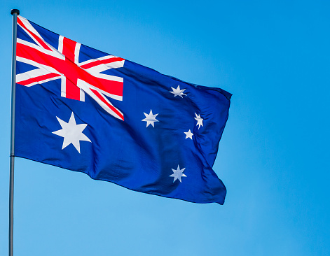 The Aussie flag fluttering in the wind against vibrant blue sky